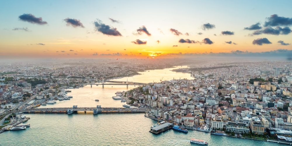 Aerial drone view of Istanbul at sunset, Turkey. Multiple residential buildings, mosques, Galata and Metro bridges over the Golden Horn waterway with floating ships